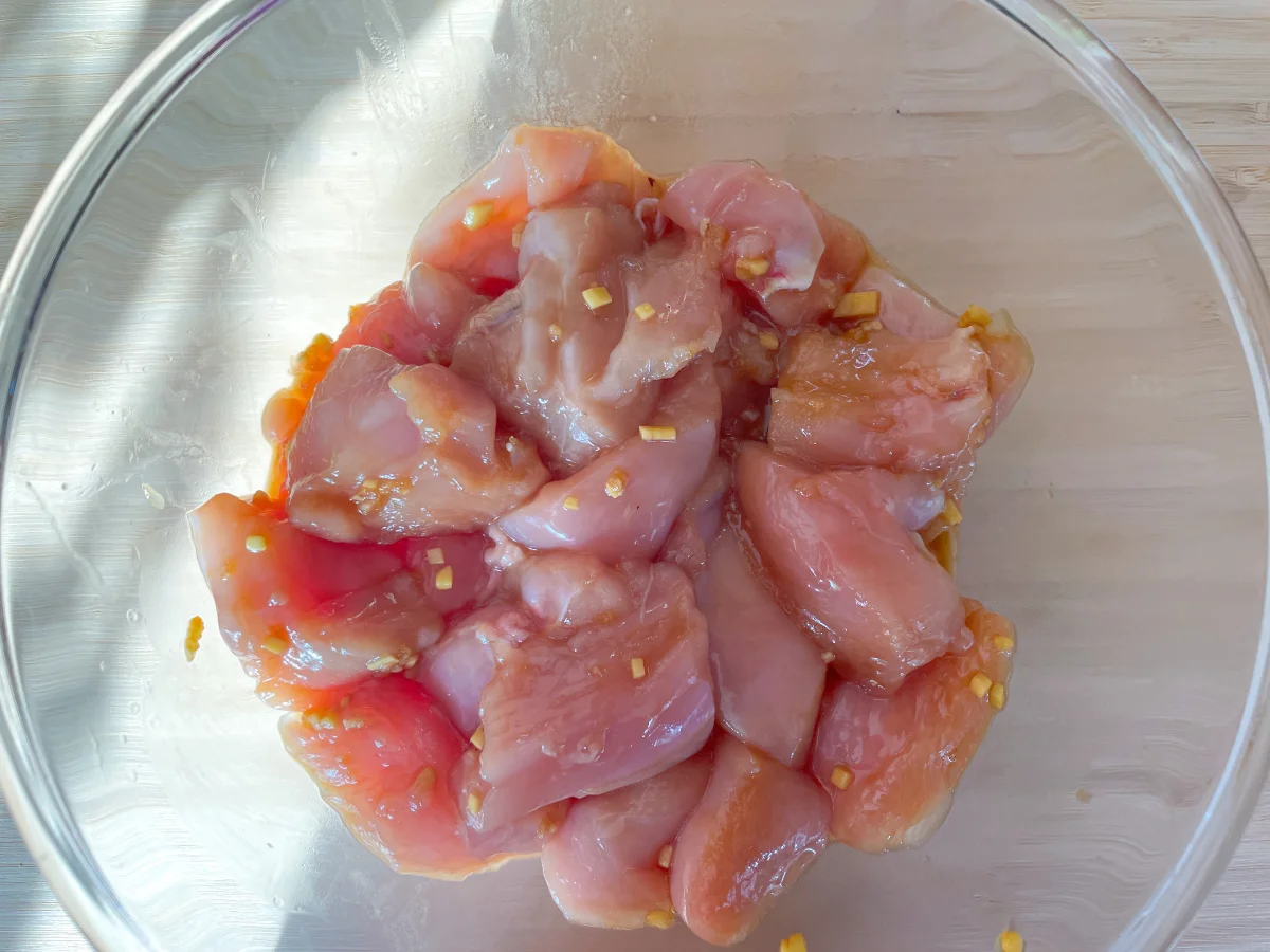 Chicken being marinaded in a large bowl