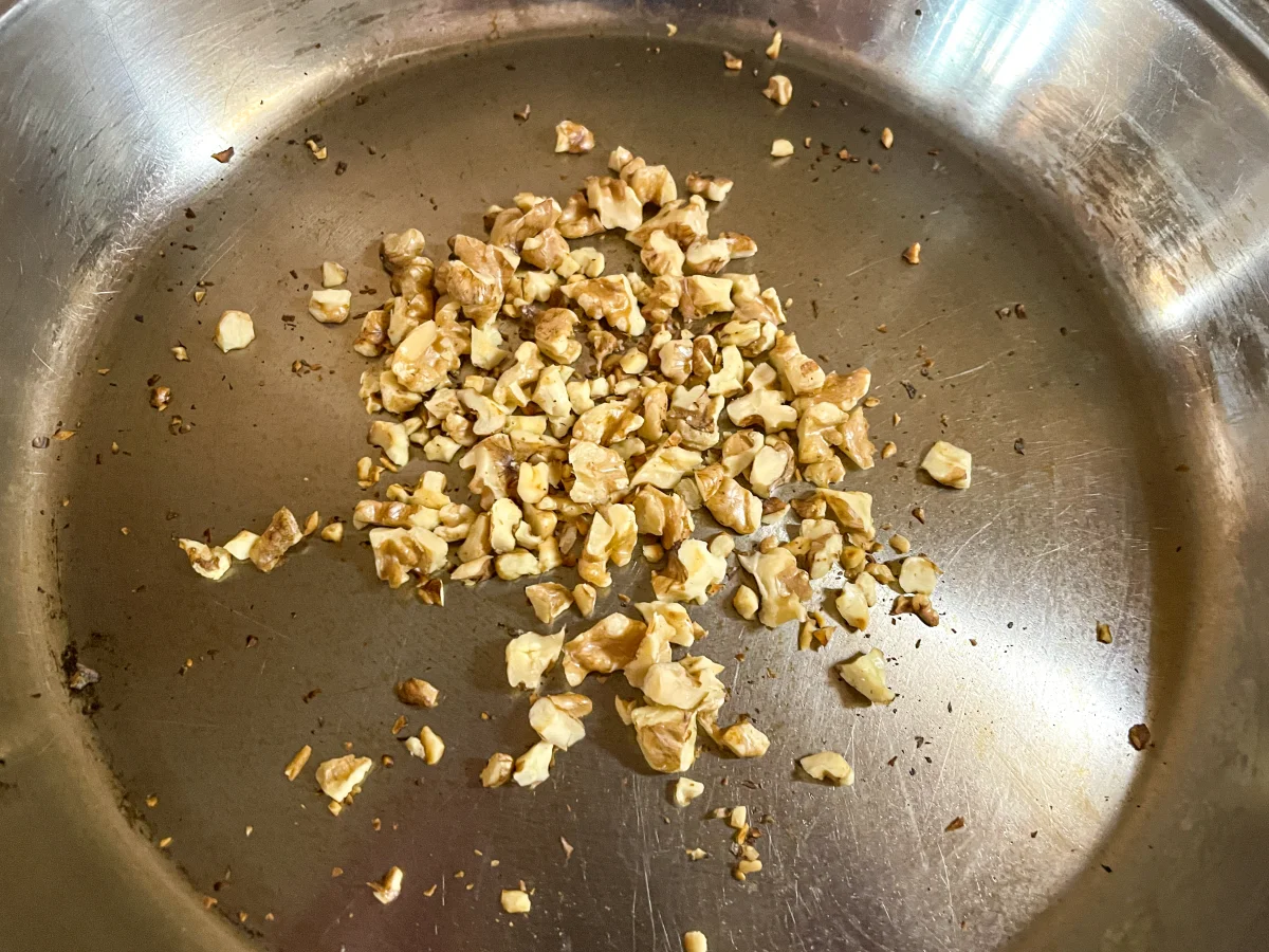 Chopped walnuts being fry roasted in a frying pan