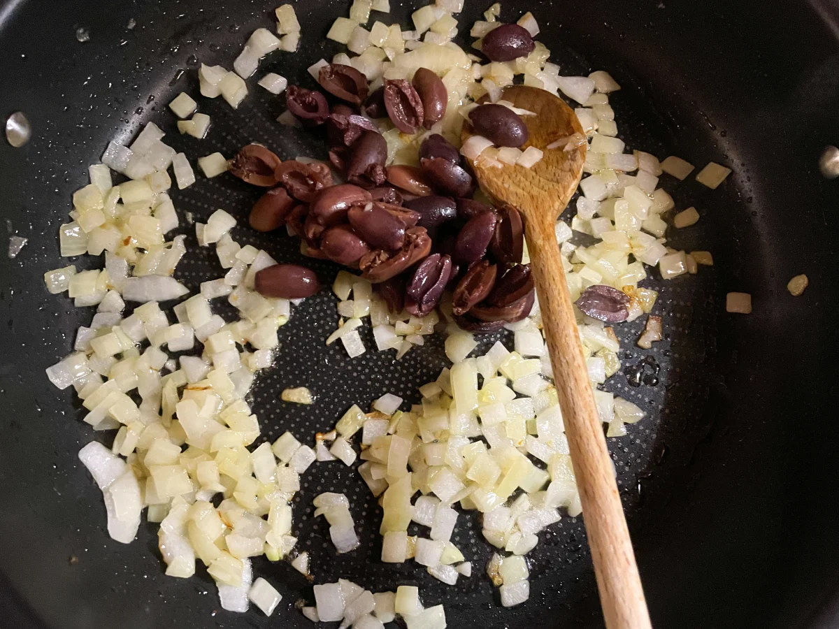 Kalamata olives and onions in a frying pan