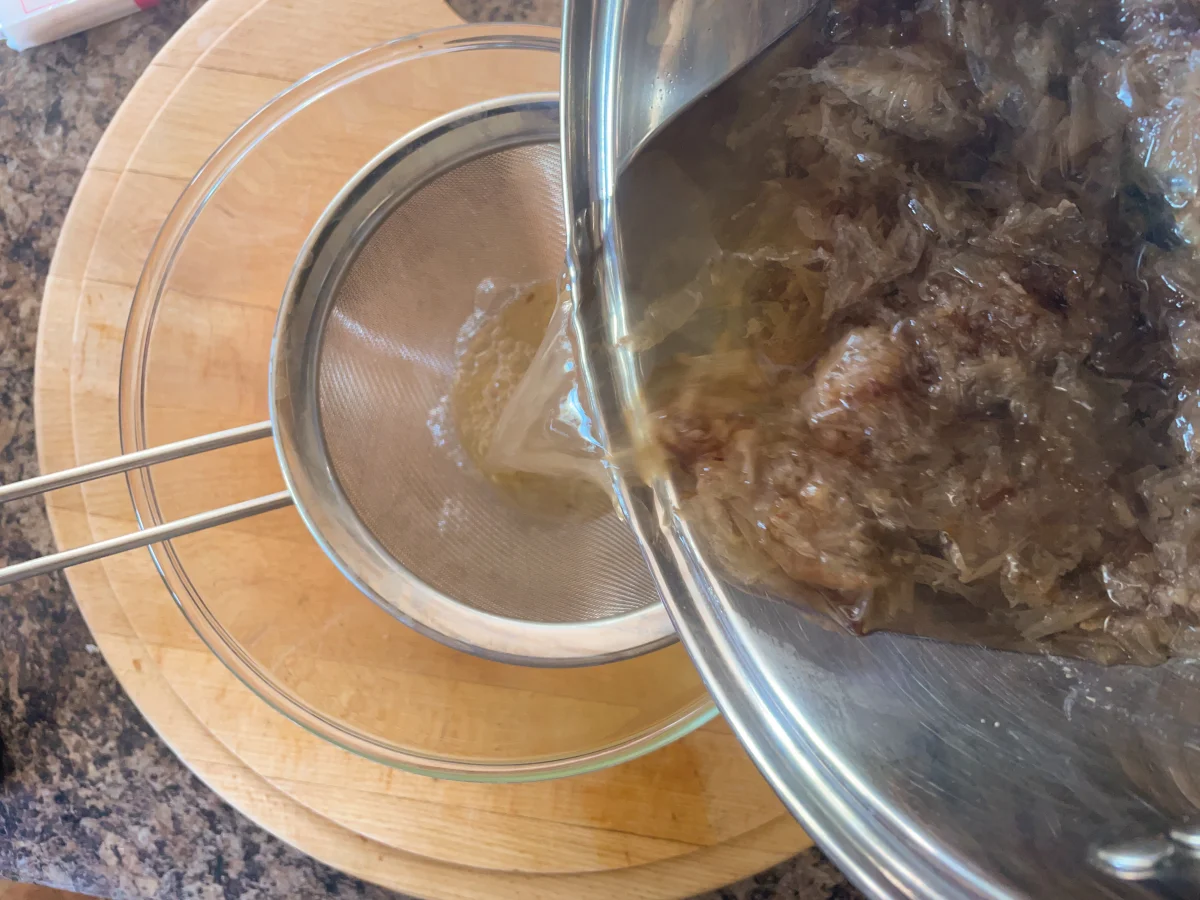 Pouring dashi stock through a chinois to remove the katsuobushi/bonito flakes