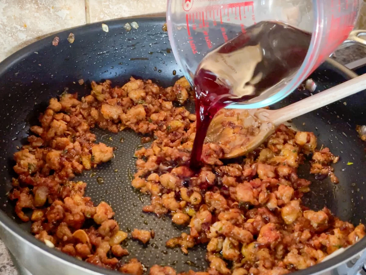 Red wine being poured into the ragu