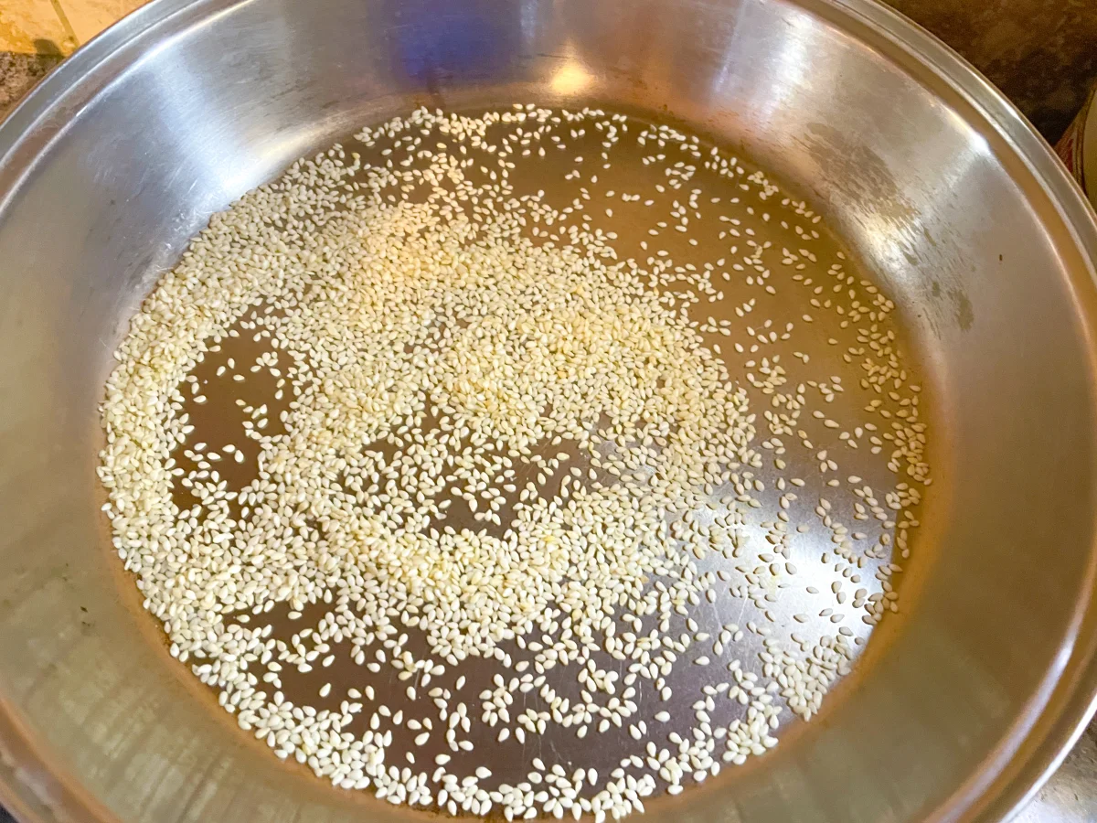 Sesame seeds being dry roasted in a frying pan/skillet