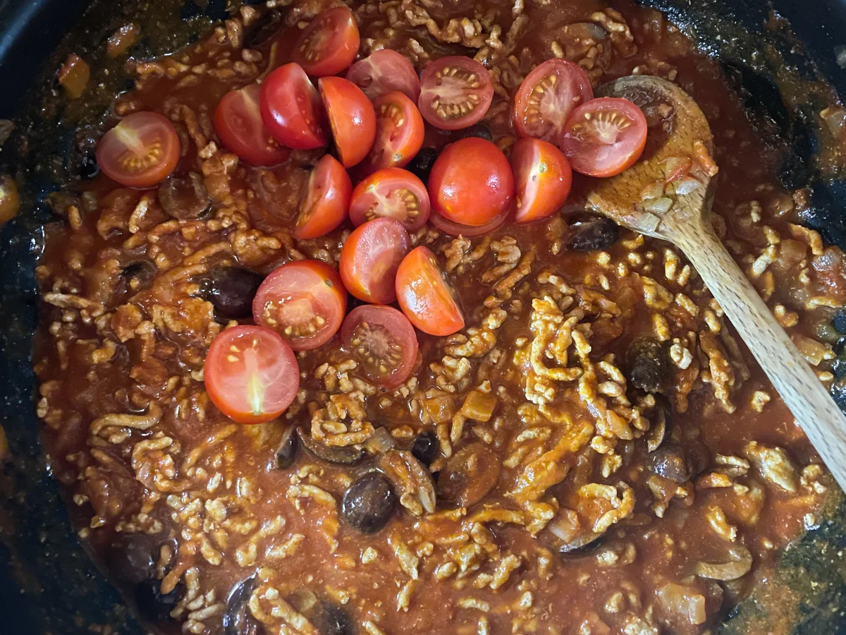 Tomatoes added to a spicy pork mince tomato sauce
